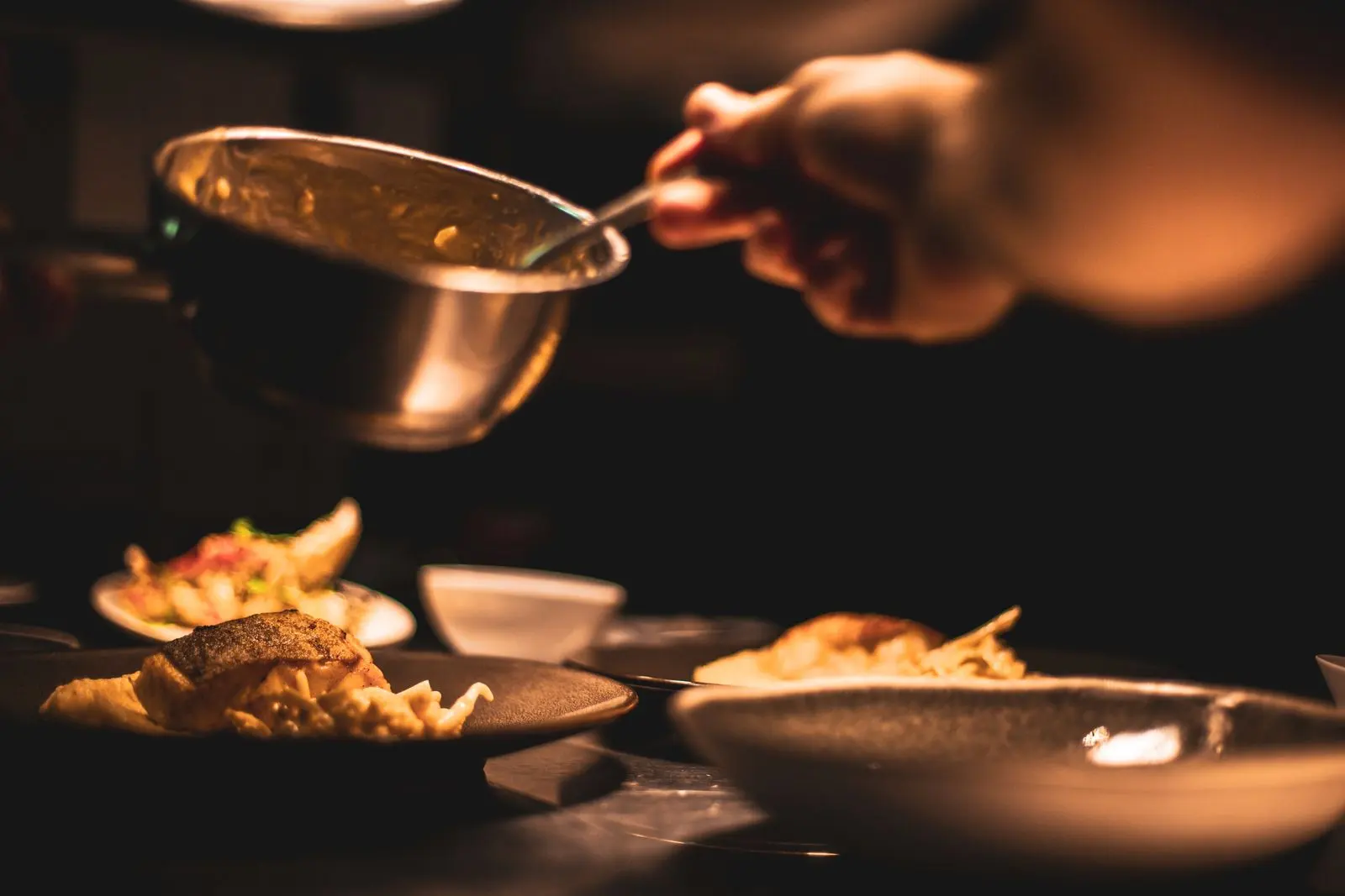 La main du chef, un bol de cuivre, le dernier geste avant le service.